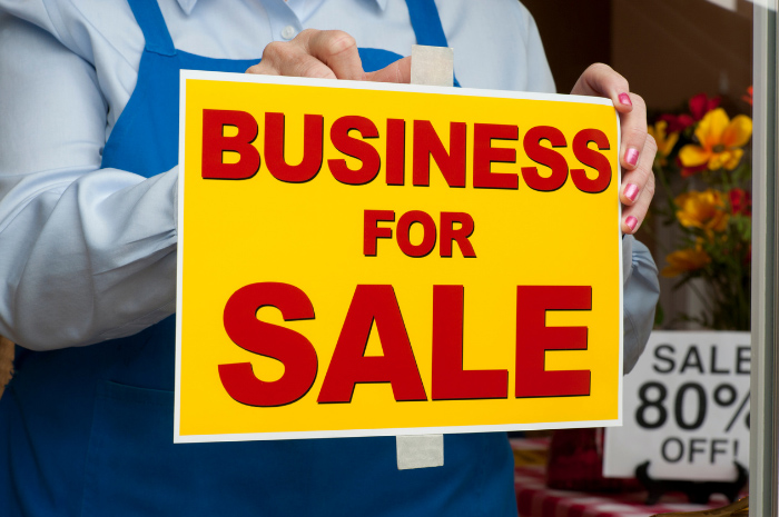 How to sell your business | DGL Accountants Mackay Florist holding up Business For Sale sign